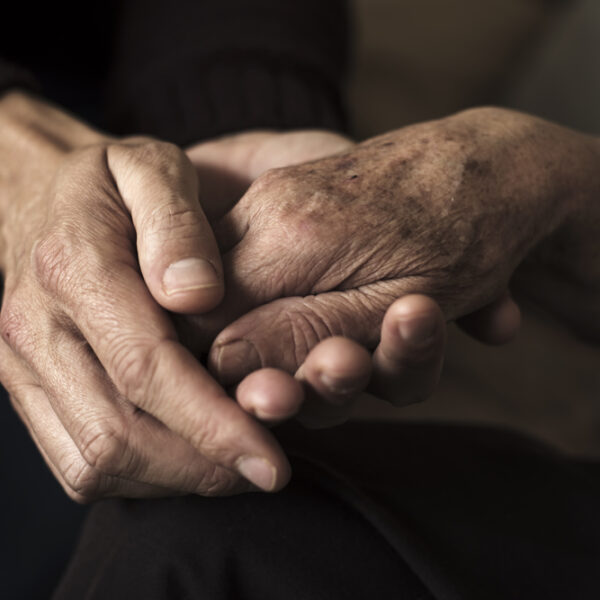 Close-up of two elderly people holding hands.